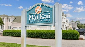 Une enseigne indiquant l’emplacement des copropriétés Mai Kai, avec une vue dégagée sur le quartier résidentiel environnant.