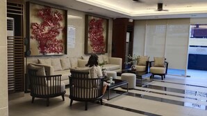 Een ruime lobby met een modern design, inclusief een zithoek met banken en fauteuils, een salontafel en decoratieve muurkunst.