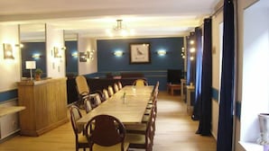 Una sala de conferencias con una larga mesa y sillas, un mostrador de recepción y un televisor.
