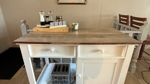 Un îlot de cuisine doté d’un plan de travail en bois, d’un grille-pain encastré et d’un petit compartiment réfrigéré.