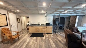 Une cuisine moderne avec des meubles en bois, un plan de travail noir et un luminaire suspendu.