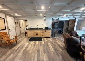 A modern kitchen with wooden cabinets, a black countertop, and a hanging light fixture. - If you’re looking for a lake view we have. Beautiful home right on the water! (Sprucedale)