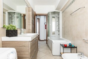 A modern bathroom with a shower, a sink, and a toilet. There is a small shelf with toiletries. - Relax Urbano con Balcone | Metro e San Siro (Milano)