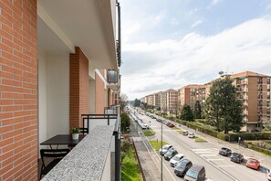 A balcony with a view of a street lined with parked cars and residential buildings. - Relax Urbano con Balcone | Metro e San Siro (Milano)
