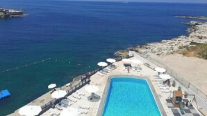 A pool area with lounge chairs and umbrellas, overlooking a body of water. - 24/7 electricity Seaview studio with beach access (Jabal Lubnan)