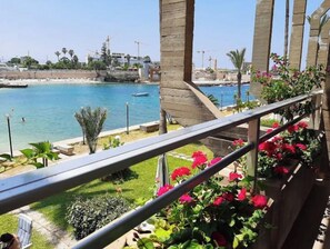 A balcony with a view of a beach and the sea.