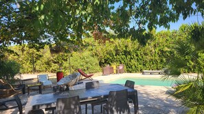 Ein Poolbereich mit Korbmöbeln, einem Tisch und Stühlen.