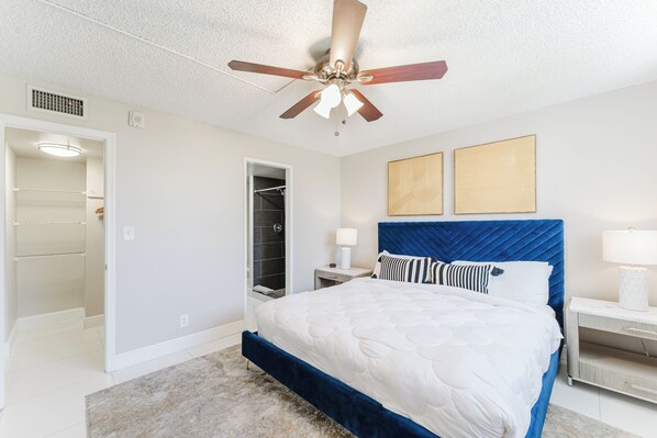 A bedroom with a bed, a ceiling fan, a walk-in closet, and two framed pictures on the wall. - Boca Raton - Across from Beach - Balcony • Pool • Parking • 2BR (Boca Raton)