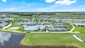 Un complejo turístico de golf con varias edificaciones, una piscina y una amplia zona verde.