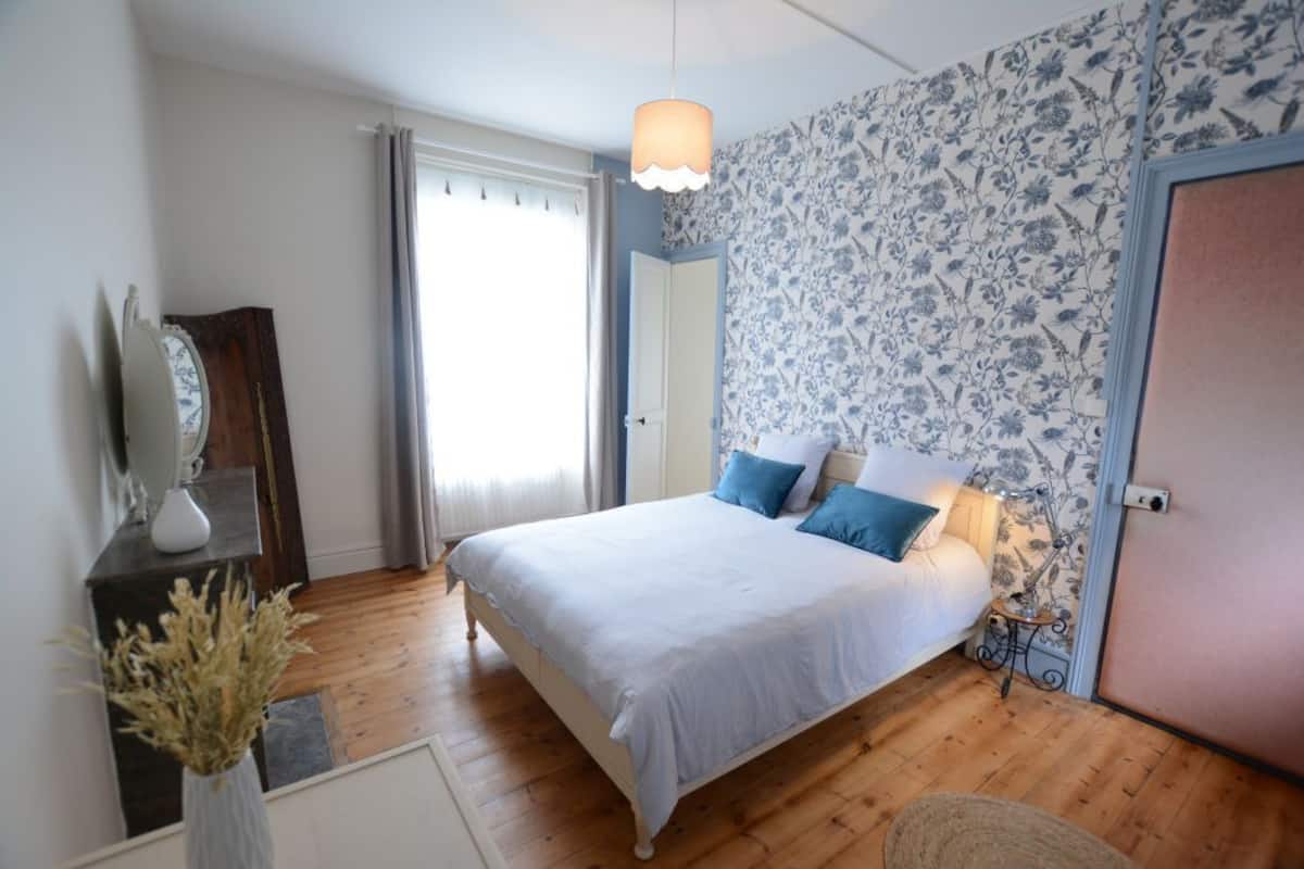 A bedroom with a bed, bedside table, and a mirror.