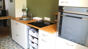 A compact kitchen with a sink, stove, and storage drawers. - Les Suites Fisel (Rostrenen)