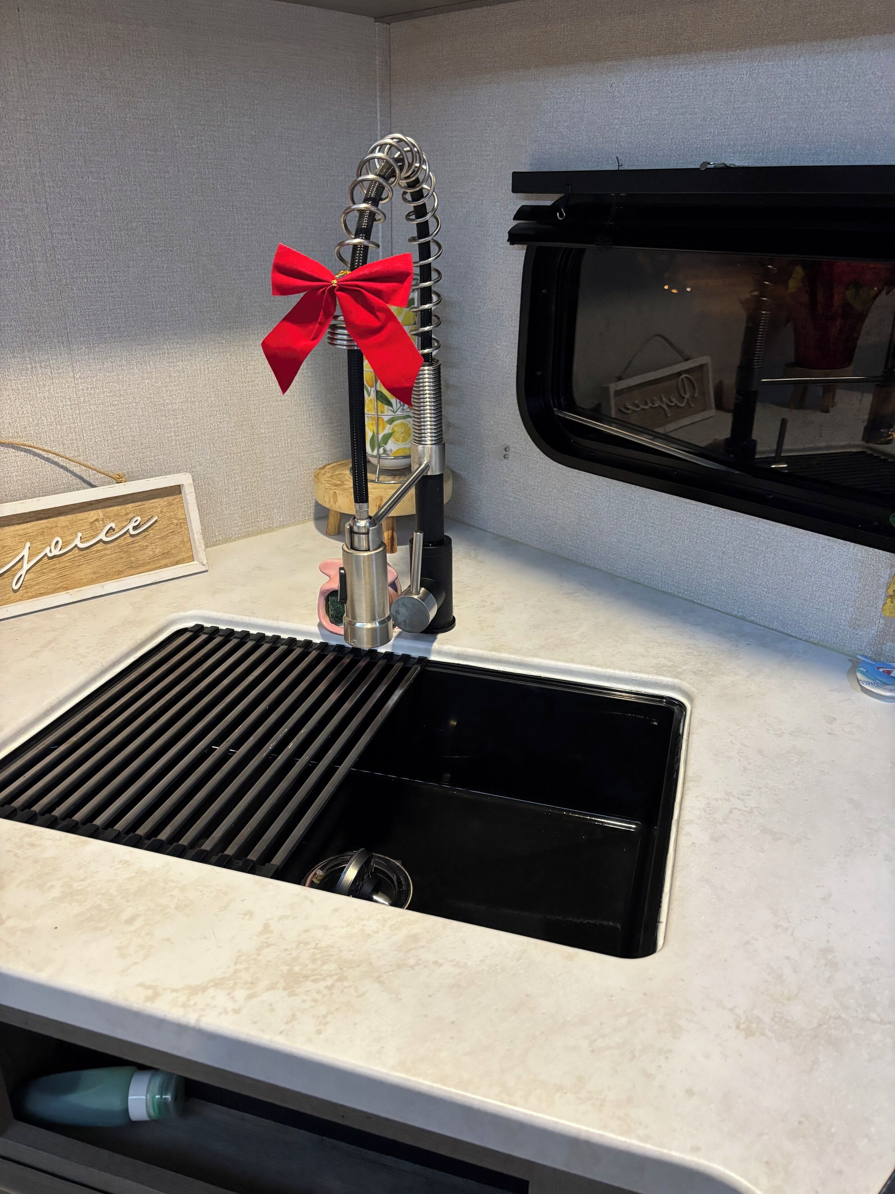 Un lavamanos de cocina con grifo de acero inoxidable, un lazo rojo y un letrero de madera con la palabra 