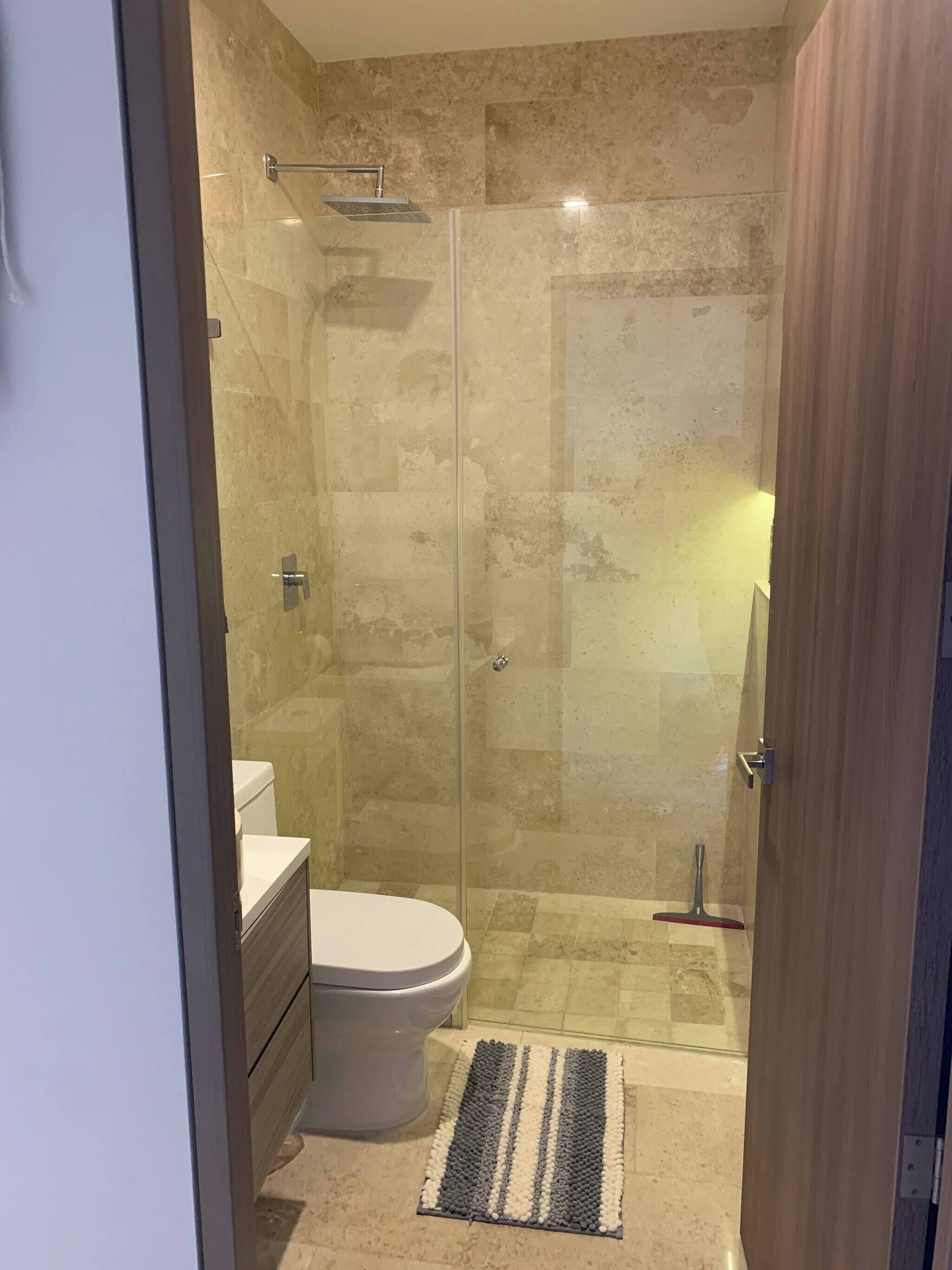 A modern bathroom with a glass-enclosed shower, a toilet, and a sink.