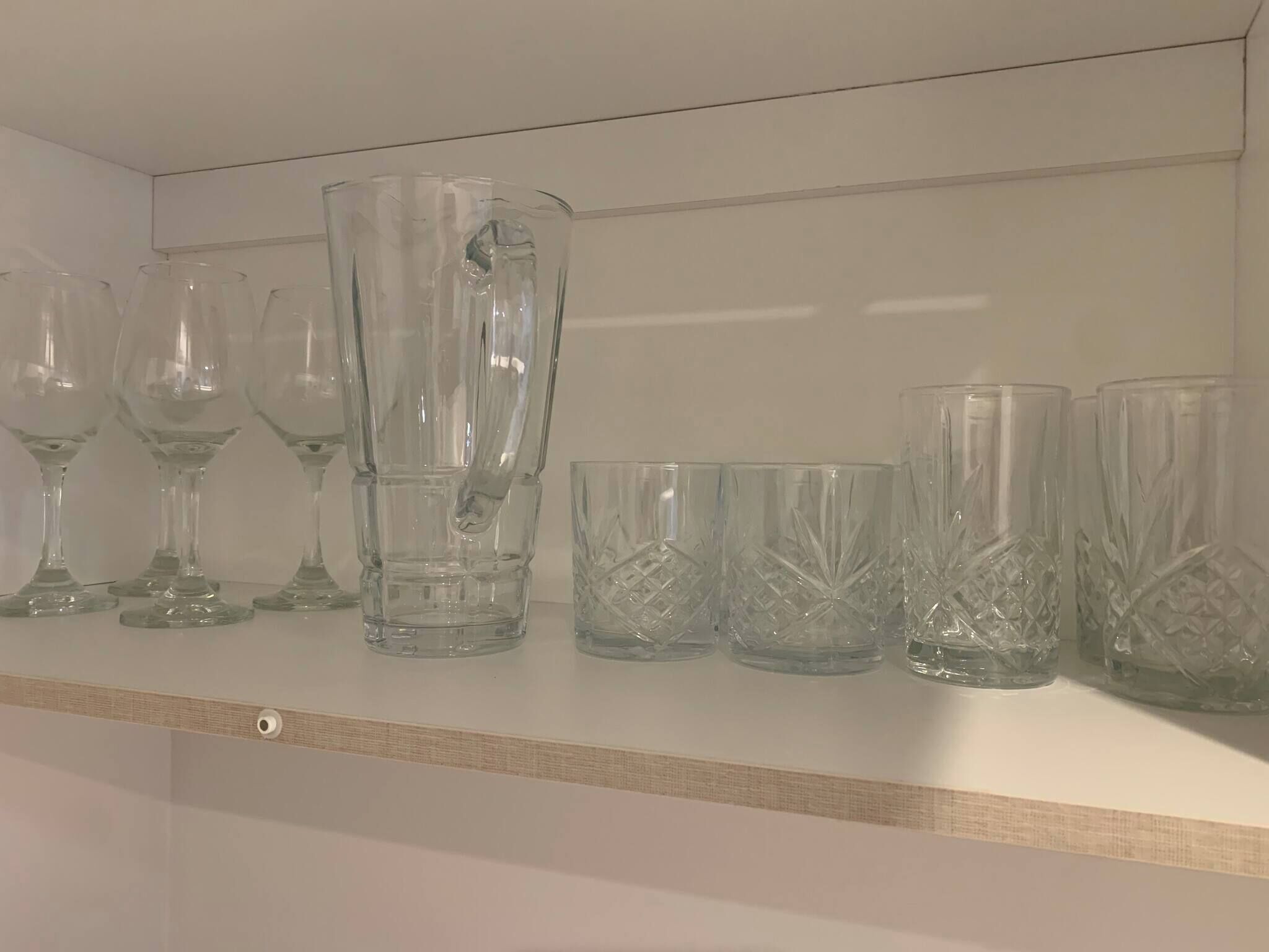 Une étagère contenant divers articles en verre, notamment des verres à vin et des verres à cocktail.