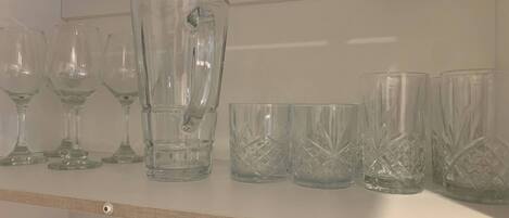 Une étagère contenant divers articles en verre, notamment des verres à vin et des verres à cocktail.