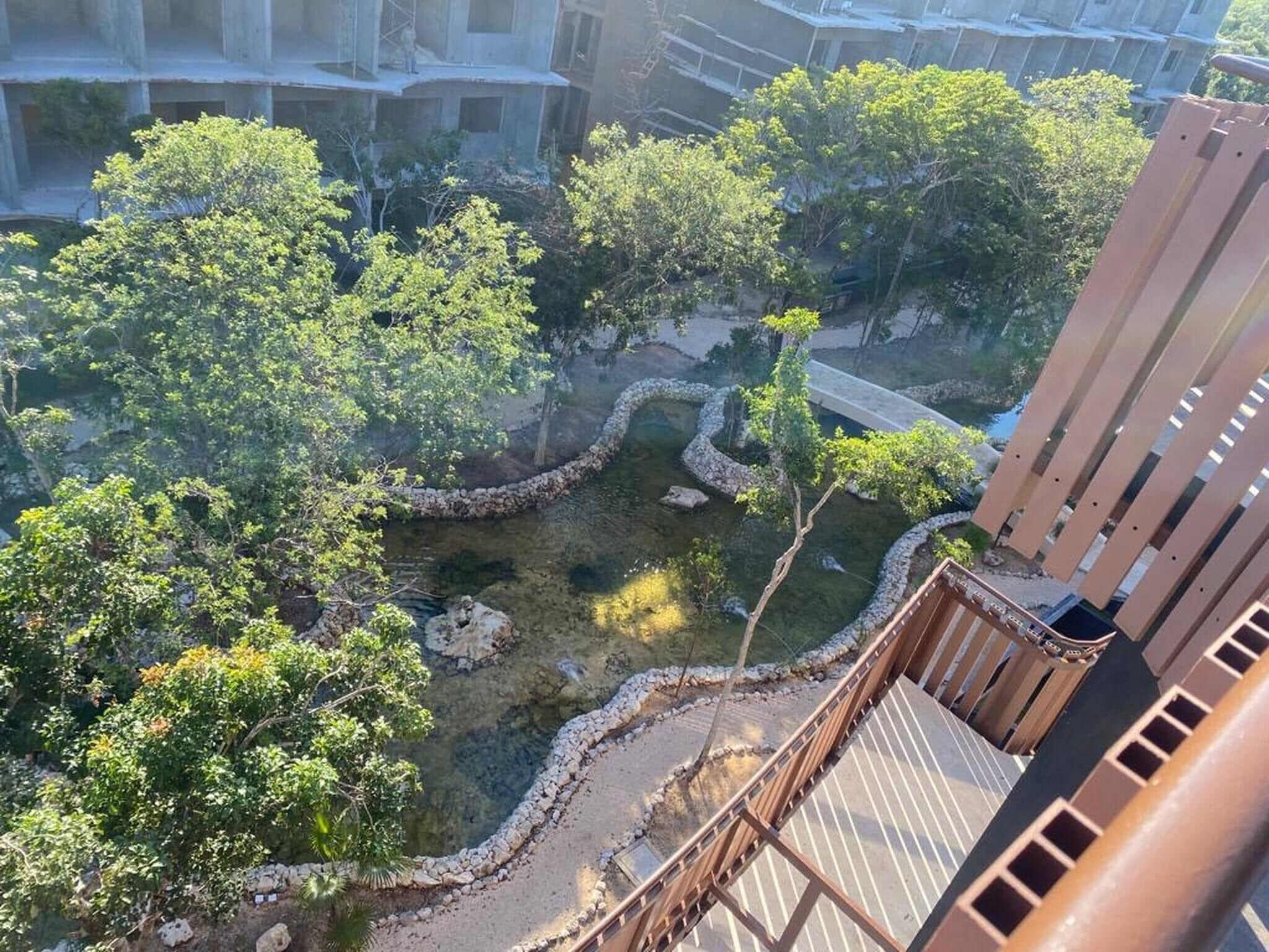 Vista de un patio con árboles, un sendero de piedra y un puente.