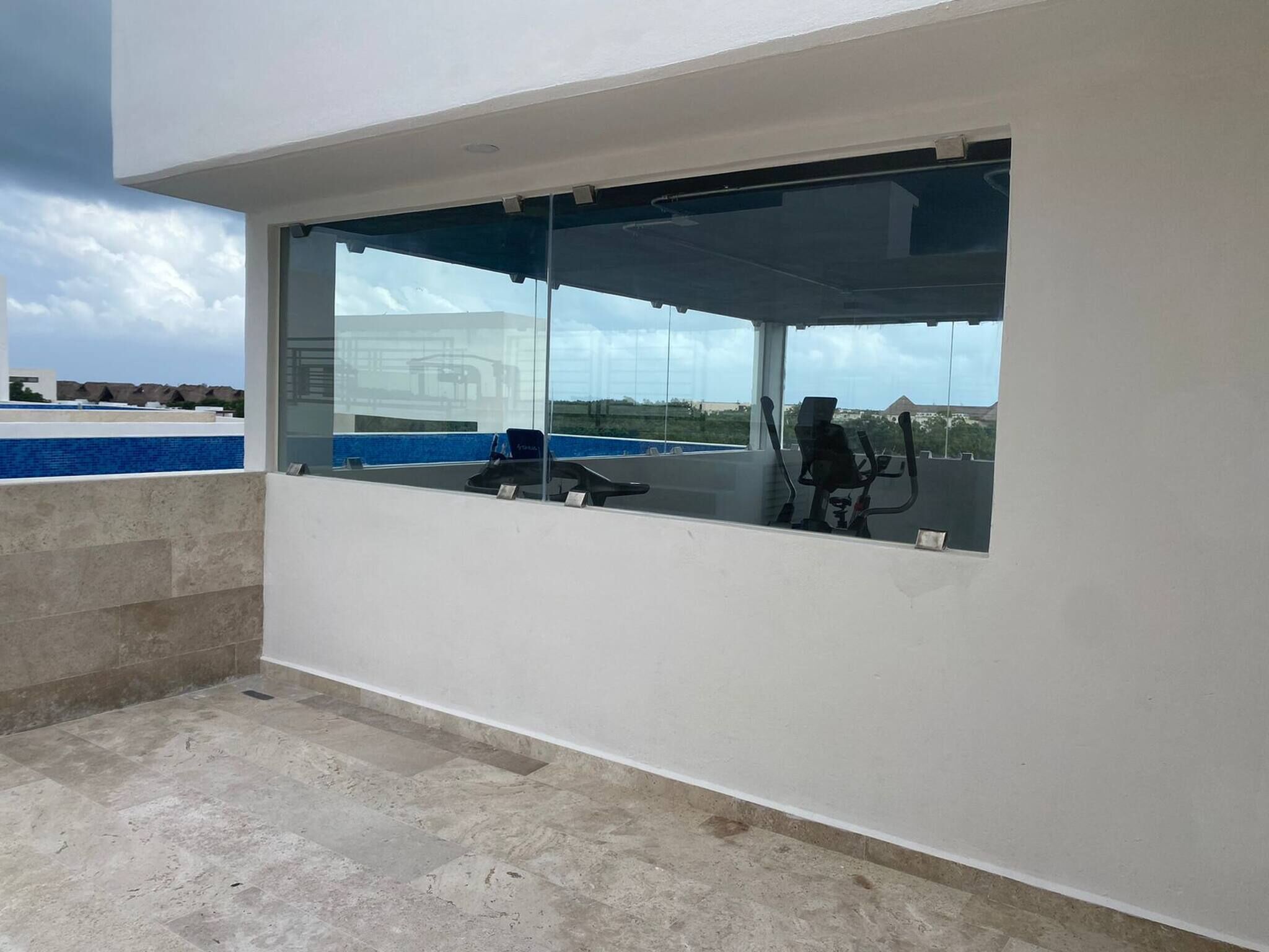 Edifici modern amb una gran finestra de vidre, una piscina i equipament esportiu.