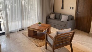 A modern living room with a wooden coffee table, a grey sofa, and a wooden chair. - ¡PH 3 Quarts Terrace and Private Pool AZ Premium! (Tulum)