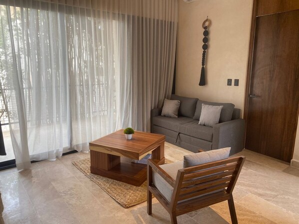 Ein modernes Wohnzimmer mit Couchtisch aus Holz, einer grauen Couch und einem Holzstuhl.