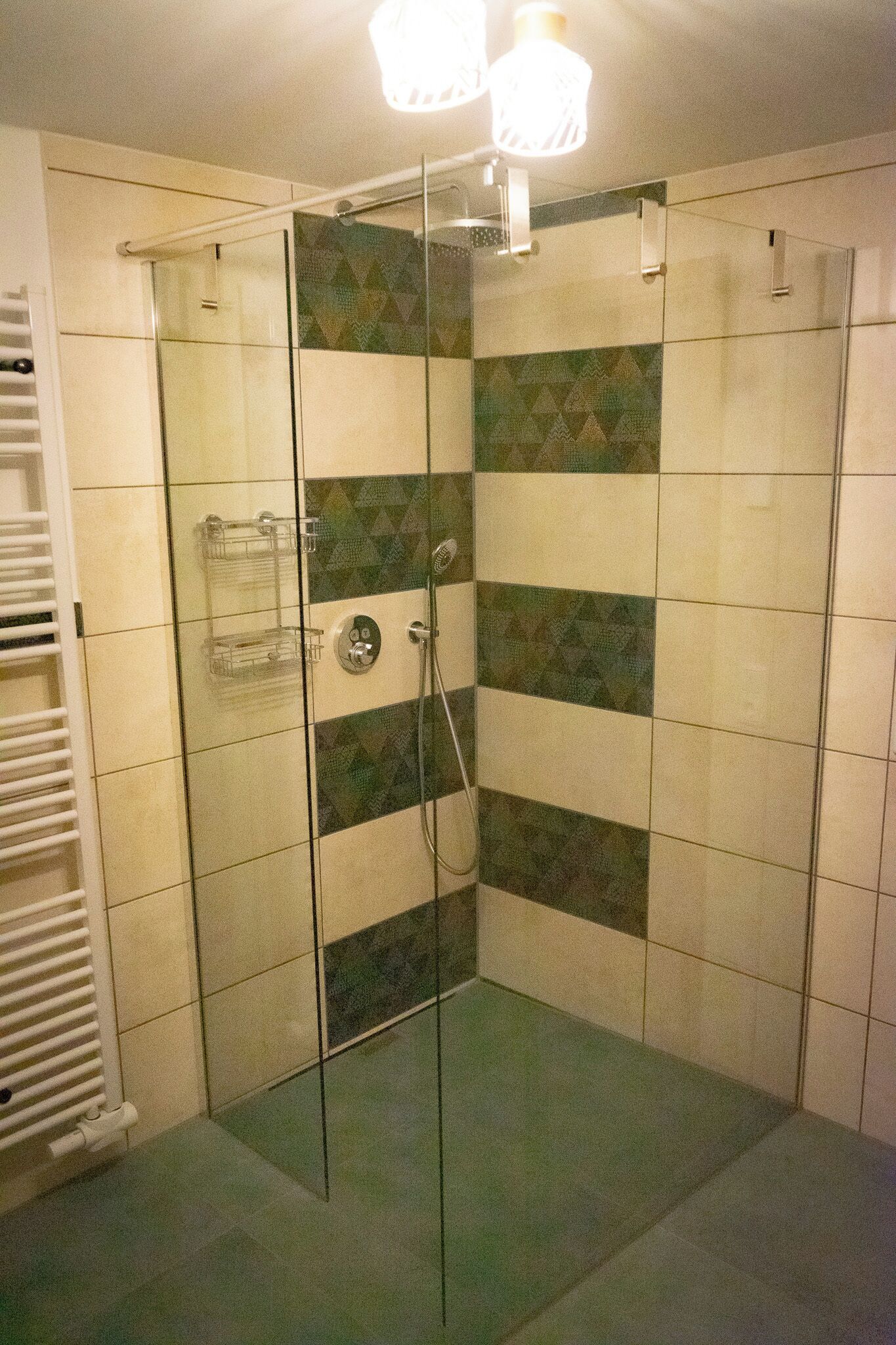Ducha con cerramiento de vidrio, un perchero blanco y un estante de vidrio.