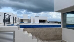 A modern rooftop terrace with a pool, steps leading to a covered area, and a view of the surrounding landscape. - Beautiful and Comfortable, 1 Bedroom! The Best in Zama! (Tulum)