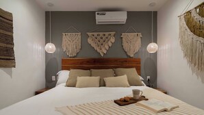 A neatly made bed with a striped bedspread, a wooden headboard, and three macramé wall hangings above it. - Beautiful and Comfortable, 1 Bedroom! The Best in Zama! (Tulum)