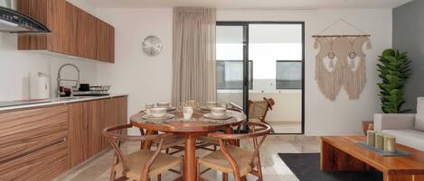 Une cuisine moderne avec des meubles en bois, une table à manger avec des chaises, un ventilateur de plafond et une porte-fenêtre coulissante donnant sur un balcon.
