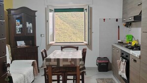 Una cocina compacta con comedor, una ventana con vista a un paisaje montañoso, un mueble empotrado y un pequeño cesto de basura.
