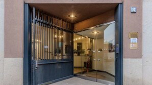 A hotel entrance with a metal gate, glass doors, and a small outdoor area.