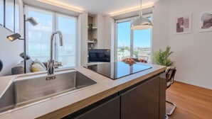 A modern kitchen with a large window, a built-in oven, and a sink.