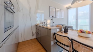 A modern kitchen with marble walls, a wooden dining table, and a large window.