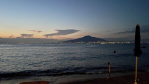 A beach with a tripod and an umbrella, a mountain in the background, and city lights across the water. - 🏖️ Vacation by the sea: panoramic balcony in Vico Equense, near Sorrento (Vico Equense)