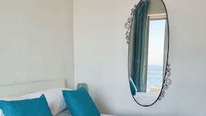 A neatly made bed with white bedding and teal pillows, a beige throw blanket, and a stack of white towels. - 🏖️ Vacation by the sea: panoramic balcony in Vico Equense, near Sorrento (Vico Equense)