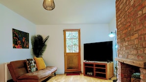 A living room with a sofa, TV, fireplace, and wooden flooring.