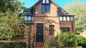 A two-story house with a brick facade, a black front door, and a sign indicating private parking.