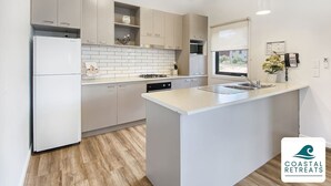 A modern kitchen with a central island, white cabinetry, and a built-in dishwasher. - 🏝 Luxury Poolside Retreat – Ramada Resort (Cowes)