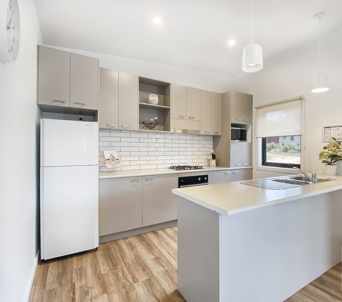 A modern kitchen with a central island, white cabinetry, and a built-in dishwasher.