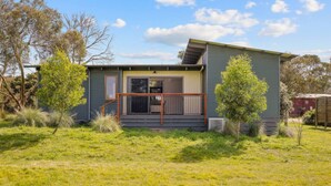 A single-story house with a front porch, a sliding glass door, and a small deck. - Luxury Hills Retreat – Villa Ramada Resort (Cowes)