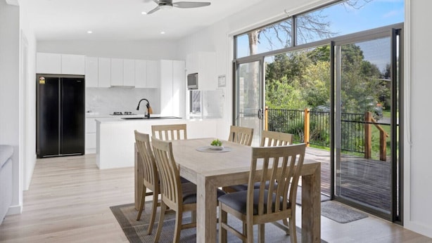 A modern kitchen with white cabinets, a black refrigerator, and a dining area with a wooden table and chairs. - Luxury Hills Retreat – Villa Ramada Resort (Cowes)