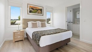 A bedroom with a bed, bedside tables, a ceiling fan, and a painting on the wall. - Luxury Hills Retreat – Villa Ramada Resort (Cowes)
