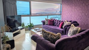 A modern living room with a large TV, purple sofa, and a view of the sea. - YC 2307 l Av Balboa 2 BDR Bay view (Panama City)