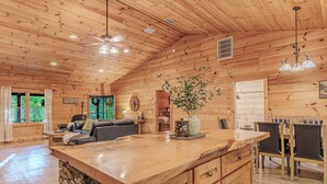 Un intérieur de chalet en bois spacieux, doté d’un grand îlot de cuisine, d’un coin repas et d’un espace salon confortable.
