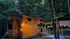 Une cabane en bois avec des fondations en pierre, une véranda et une petite terrasse.