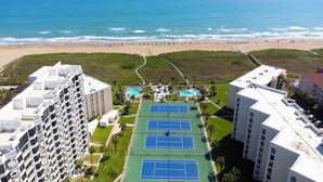 Un hôtel de grande hauteur doté de plusieurs courts de tennis, d’un espace piscine et offrant une vue sur la plage.