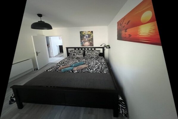 Un dormitorio con una cama, un cuadro de una puesta de sol y una puerta que da a otra habitación.