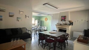 Ein Wohnzimmer mit Esstisch, Stühlen, einer Couch und einem Kamin.