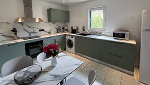 A modern kitchen with a marble countertop, built-in appliances, and a dining area with a vase of flowers. - Villas Maristella, spacious and comfortable Oriente 2 steps from the beach! (Aregno)