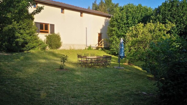 A house with a garden, a dining table, and a blue umbrella.