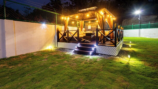 Un espace extérieur bien éclairé, aménagé avec une terrasse en bois et des marches menant à celle-ci, entouré d’une clôture et d’une pelouse.