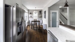 Una cocina moderna con una isla central, electrodomésticos de acero inoxidable y un comedor con candelabro.